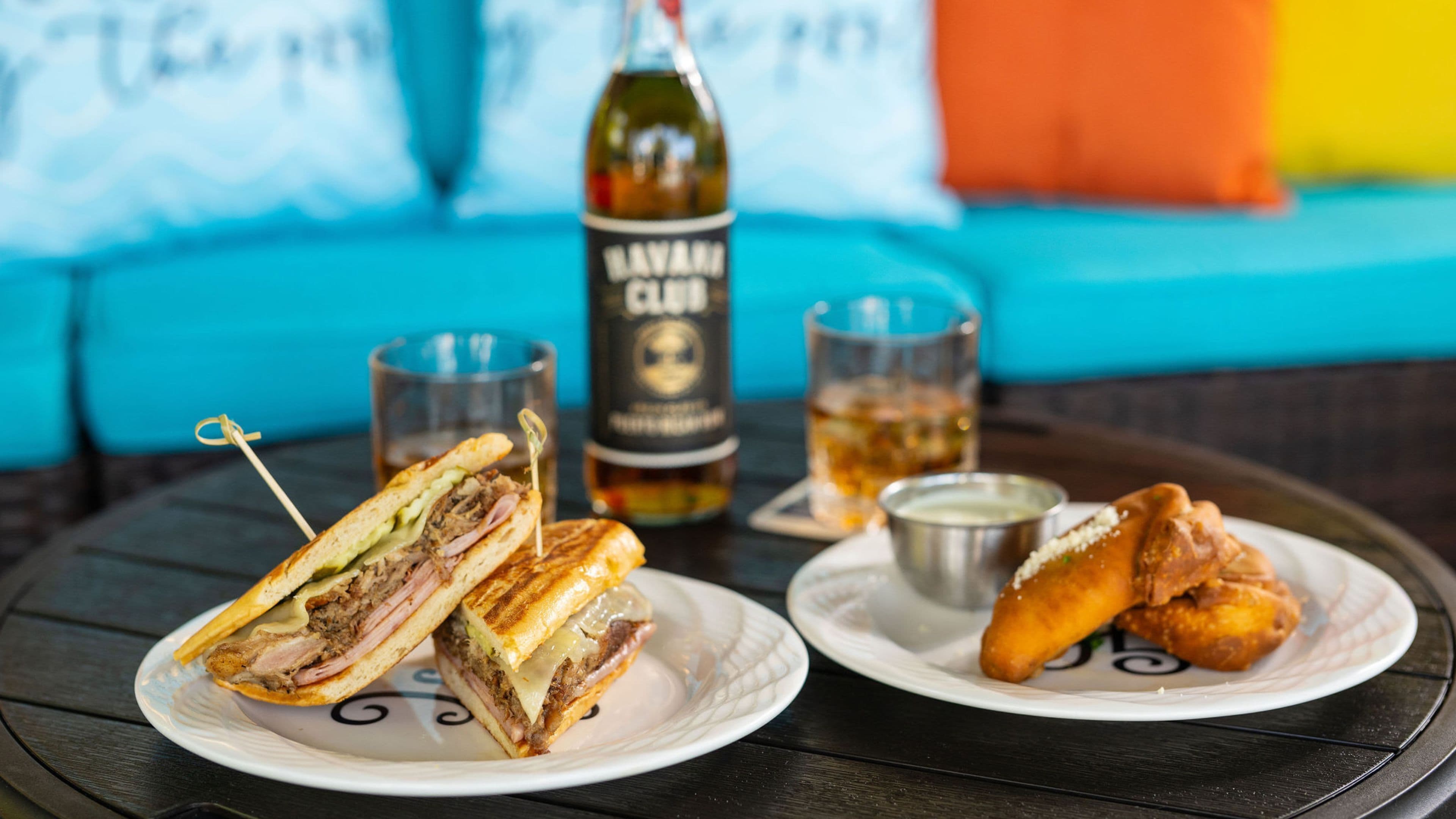 A table with a sandwich, a bottle, and two glasses.
