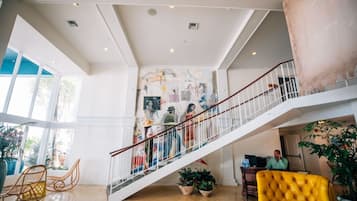 Um interior amplo com escadas, janelas grandes e diversas obras de arte.
