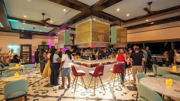 A busy bar area with high stools and a bar counter, surrounded by tables and chairs.