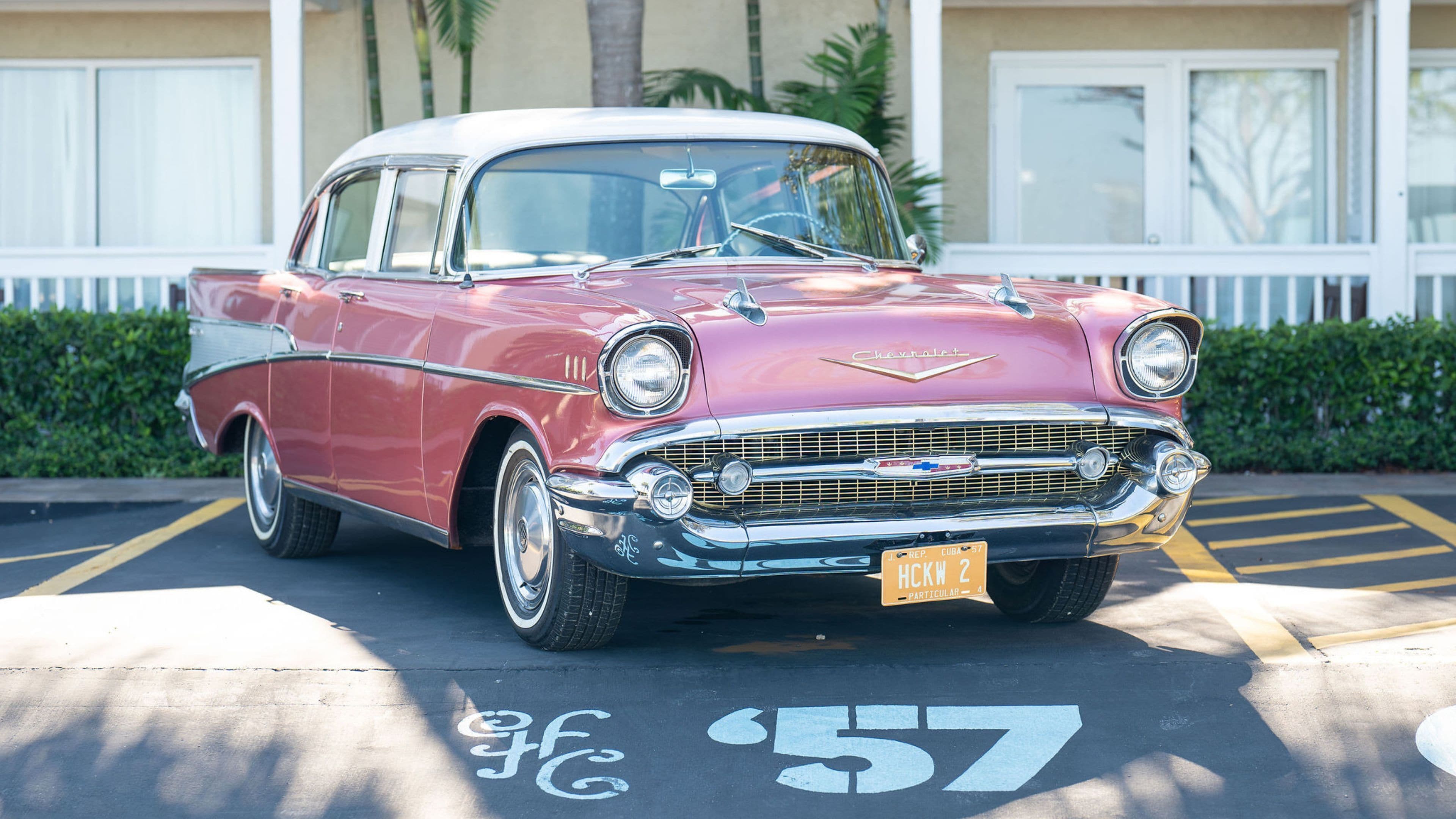 Un coche antiguo rojo y blanco estacionado en un espacio de estacionamiento marcado '57'.