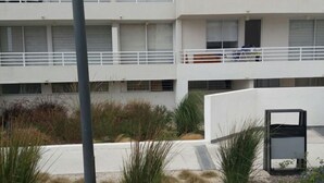 A multi-story building with balconies, a central courtyard with plants, and a trash bin. - Depto Maria Aprilla 2 Piso (La Serena)