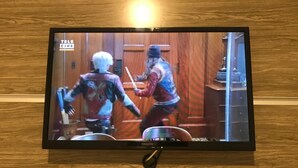 A television mounted on a wooden wall displaying a scene from a video game.