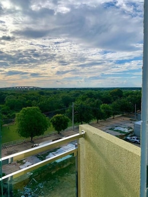 A balcony with a view of a bridge and greenery.