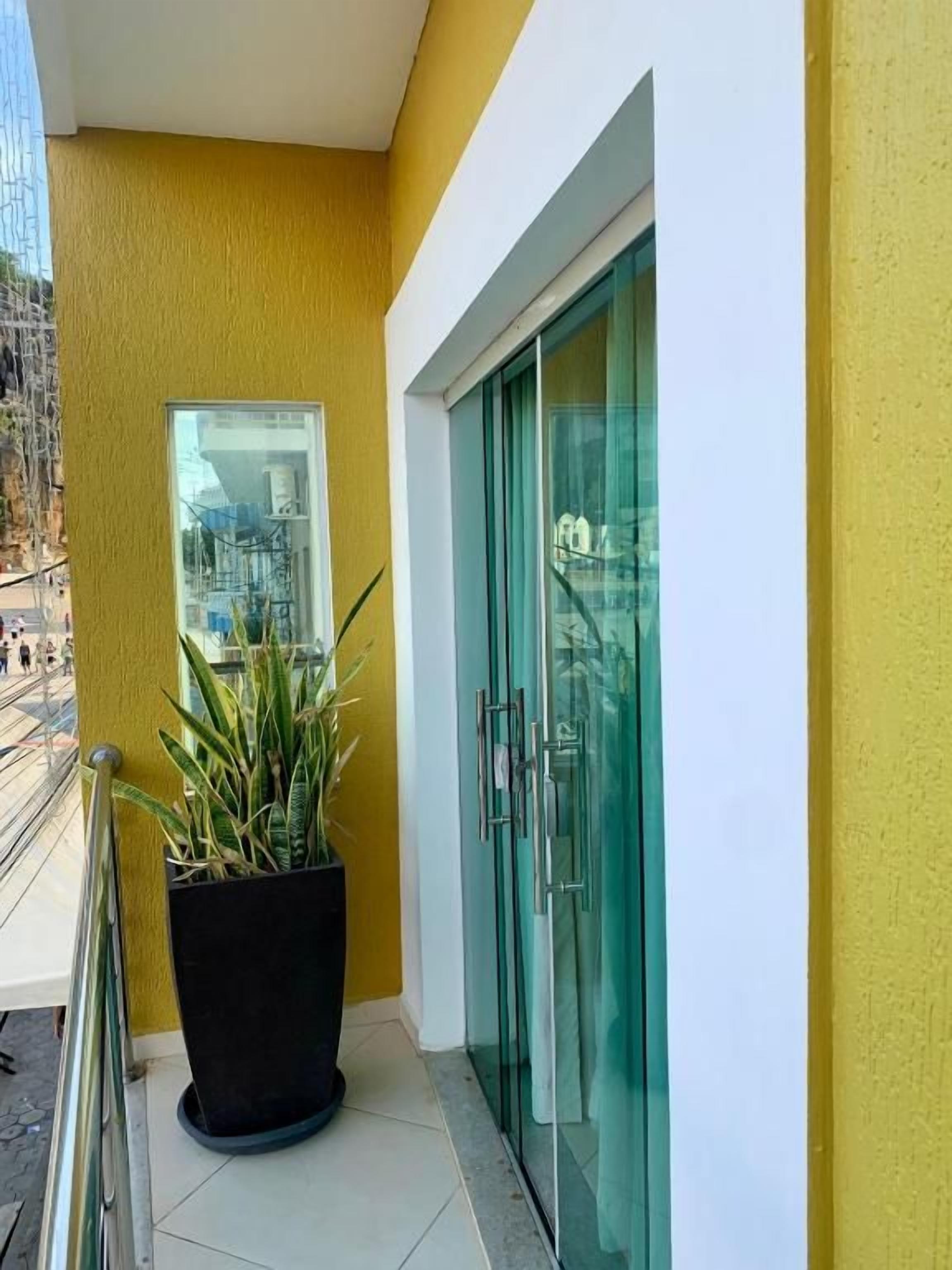 Fachada de un edificio con una pared amarilla, un puerta de cristal y una planta en maceta.