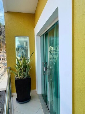 Fachada de un edificio con una pared amarilla, un puerta de cristal y una planta en maceta.