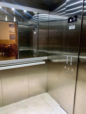 A metallic elevator interior with a reflective surface and a control panel with buttons. - Hotel Grutta (Bom Jesus Da Lapa)