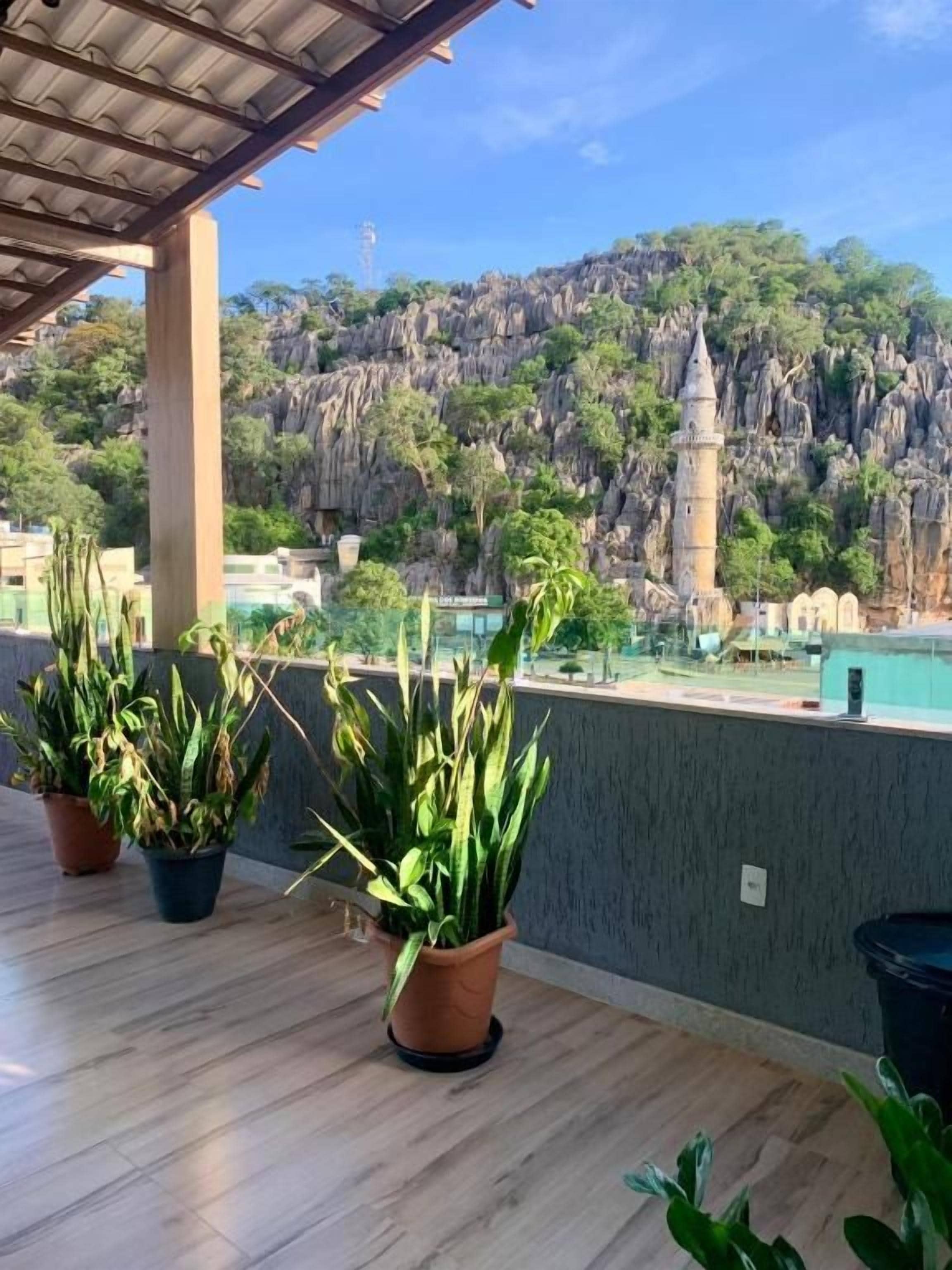 Ein Balkon mit Blumentöpfen und Blick auf einen Berg und einen Turm.