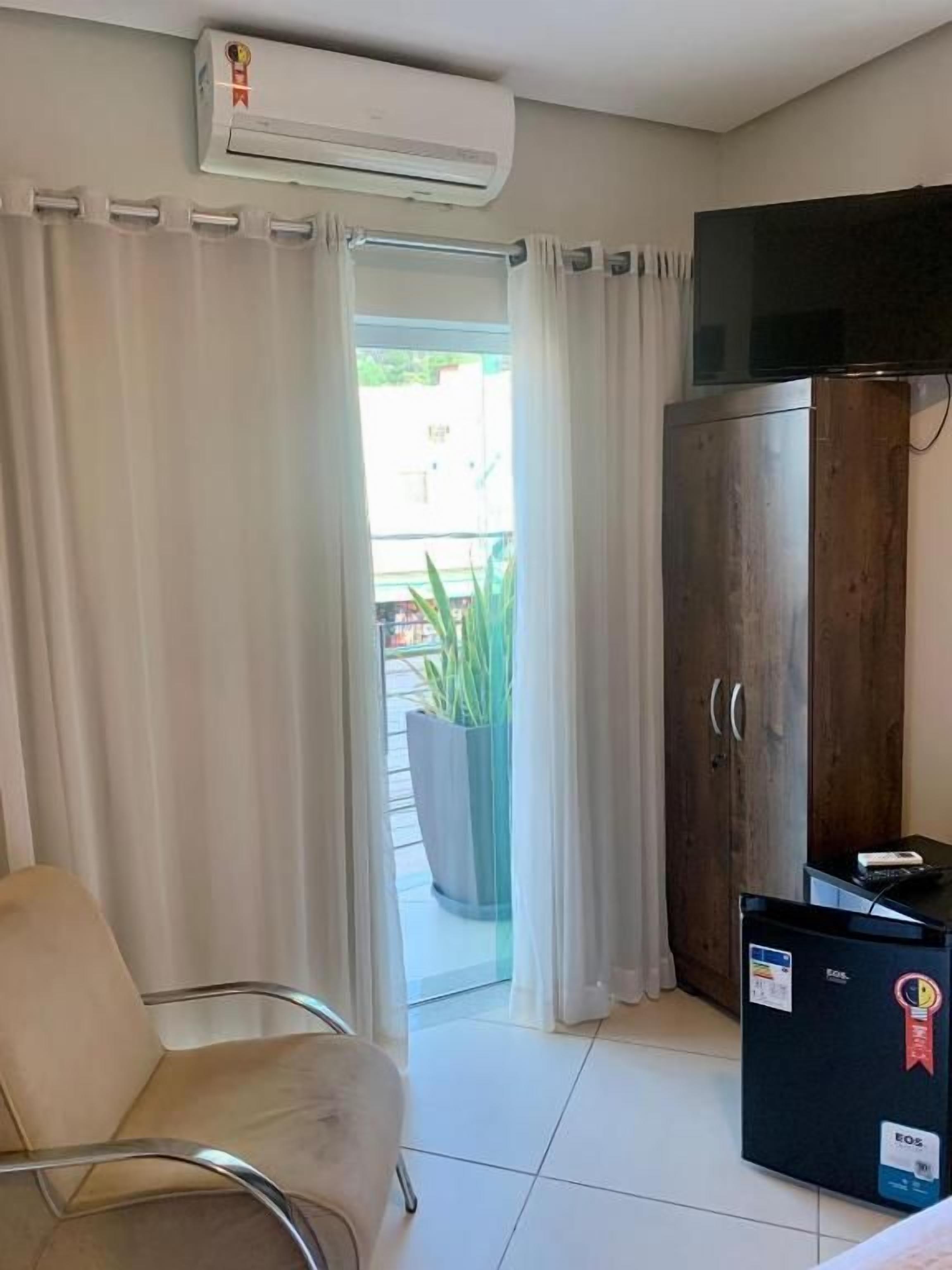 Habitación de hotel con cama, una silla, armario, aire acondicionado y televisor.