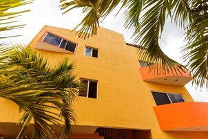 Un edificio de varios pisos con fachada amarilla, múltiples ventanas y balcones.