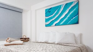 A hotel room with a bed, a large abstract painting, and a window with a grey blind. - Kaam Accommodations (Puerto Morelos)