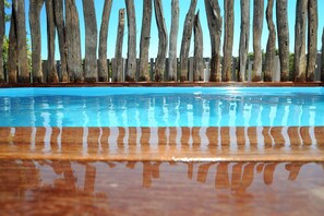 Una piscina con postes de madera y un muelle de madera en primer plano.