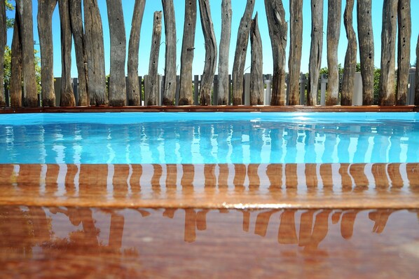 Una piscina al aire libre, sombrillas, sillones reclinables de piscina