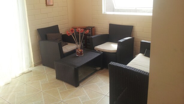 A corner seating area with wicker furniture, a small table, and a vase with flowers. - Casa en Bahia Inglesa (Caldera)