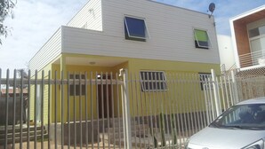 A two-story house with a white exterior and yellow lower section. - Casa en Bahia Inglesa (Caldera)