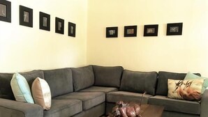 Ein Wohnzimmer mit grauem Sofa, einem Holztisch und einer kleinen Pferdestatue.