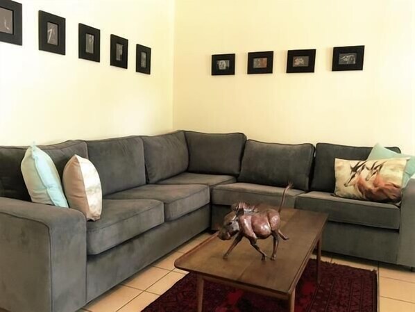 Sala de estar com um sofá cinza, uma mesa de centro de madeira e uma pequena estátua de cavalo.