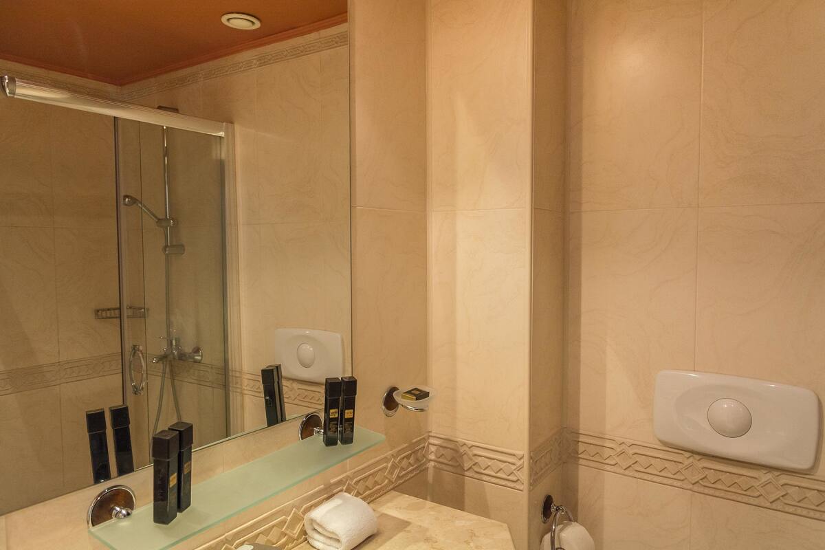 Une salle de bain dotée d’une douche à parois de verre, d’un meuble-lavabo en verre et d’un porte-serviettes.