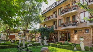Een hotel met meerdere verdiepingen, balkons, een verzorgde tuin en buitenzitplaatsen.