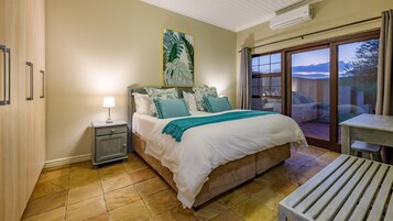 Un dormitorio con cama, mesita de noche y vistas al exterior.