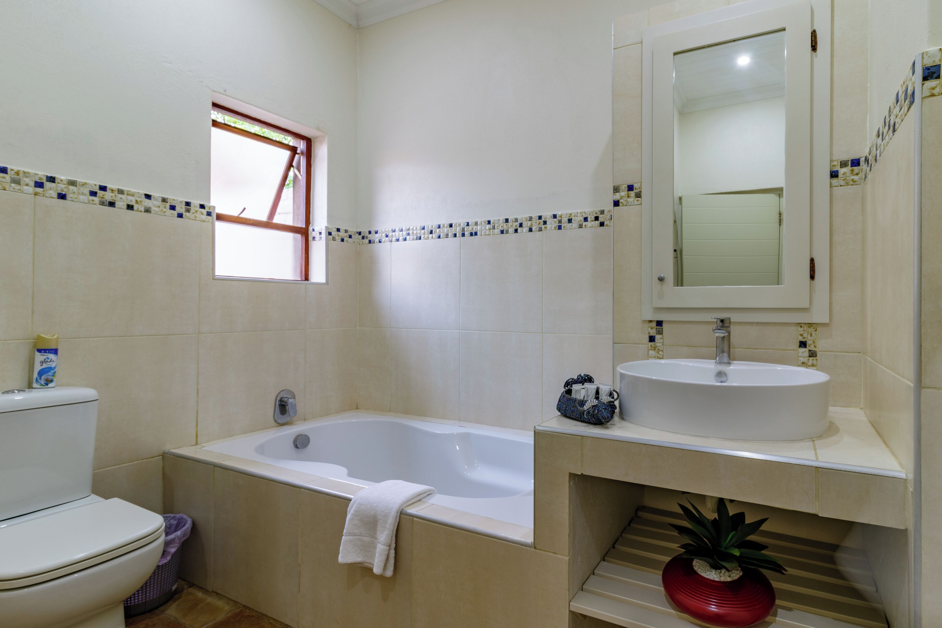 A bathroom with a bathtub, toilet, sink, and a window.