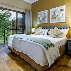 A large bed with a wooden headboard, white bedding, and multiple pillows. There are two wall-mounted artworks above the bed.