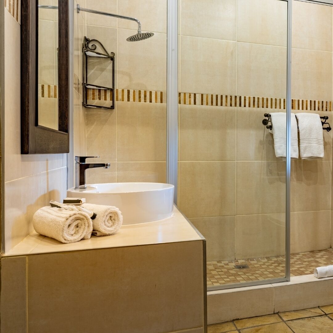 A modern bathroom with a white sink, a glass shower enclosure, and a mirror with a towel rack.