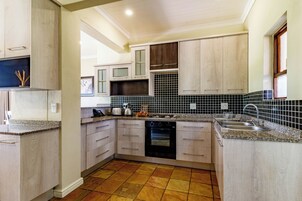 A kitchen with light wood cabinets, a black oven, and a tiled backsplash.