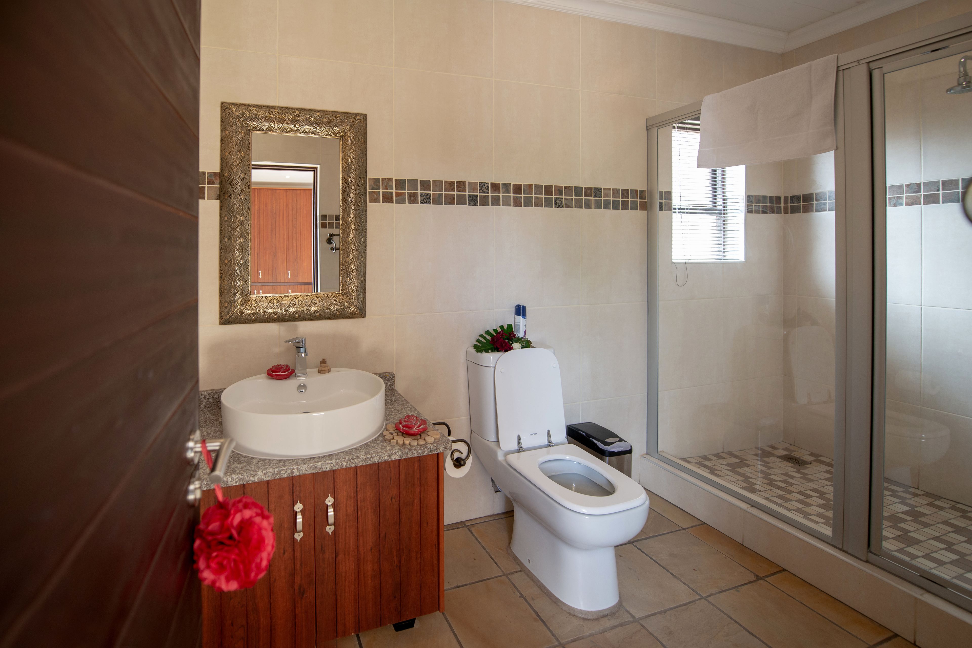 A bathroom with a wooden vanity, white sink, and toilet.