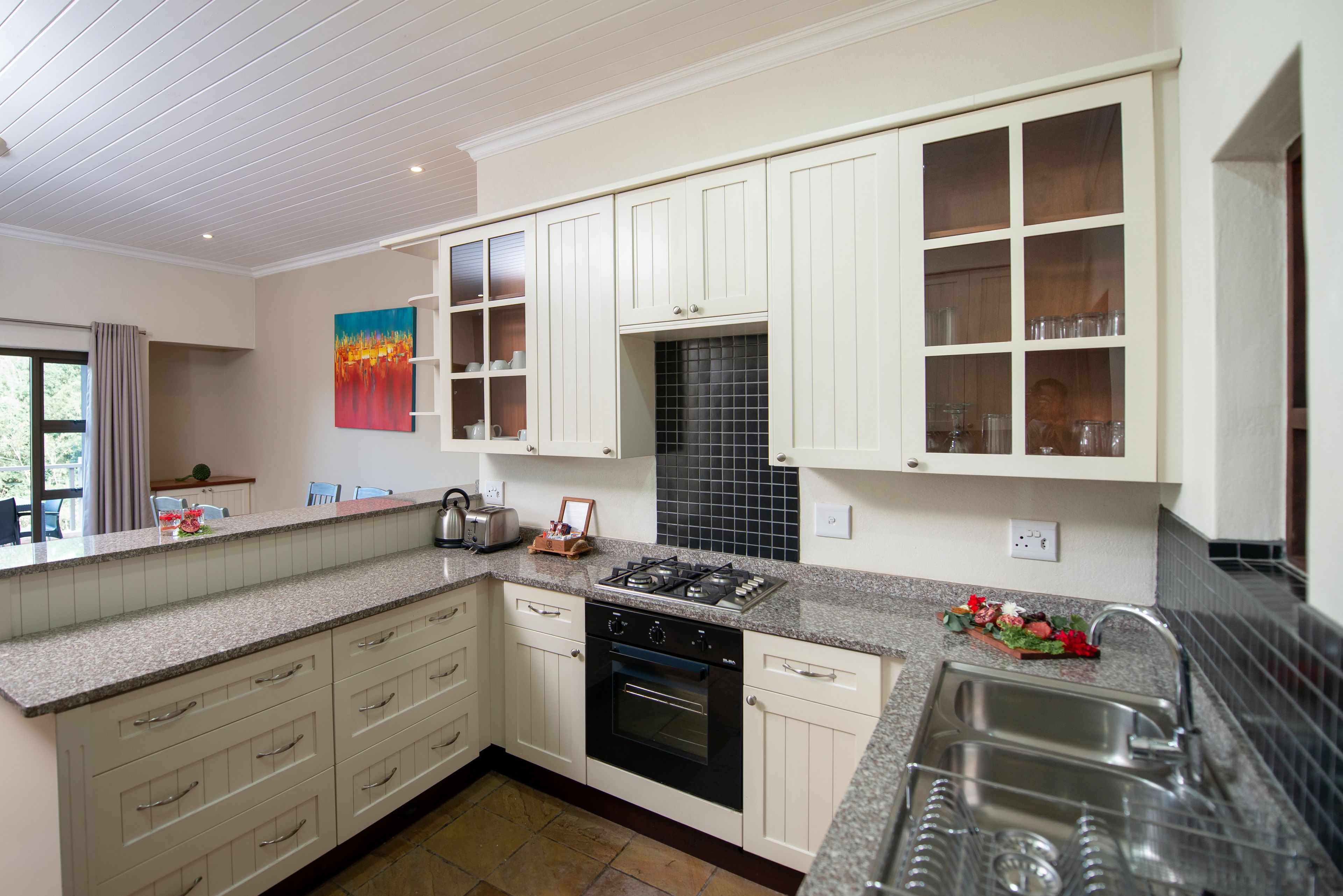 A modern kitchen with white cabinetry, a granite countertop, a gas stove, and a built-in oven.
