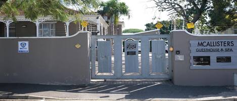 A gated entrance to a property named 'McAllisters Guesthouse & Spa' with a sign indicating 'No Parking in Front of This Gate'.