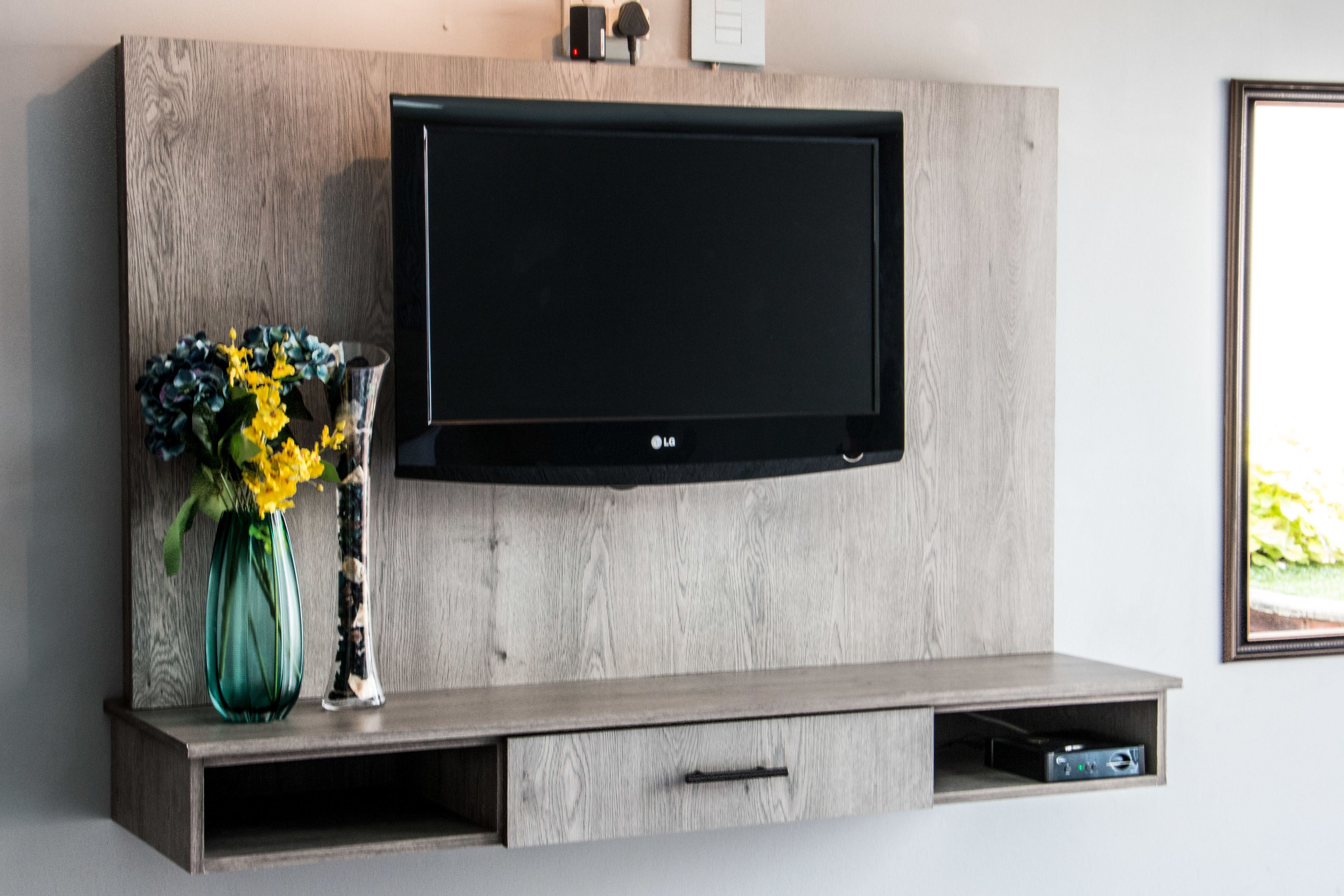 Un téléviseur à écran plat fixé à un mur en bois, avec une étagère en dessous.