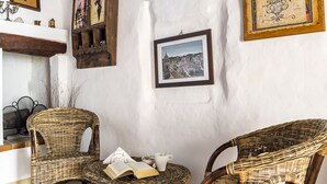 Una habitación acogedora con dos sillas de mimbre, una mesita pequeña y una pared blanca decorada con cuadros.