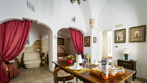 Un comedor con una mesa de madera dispuesta para dos personas, un sofá y una cama al fondo.