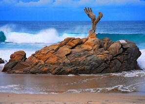 A rocky outcrop with a sculpture on a beach.