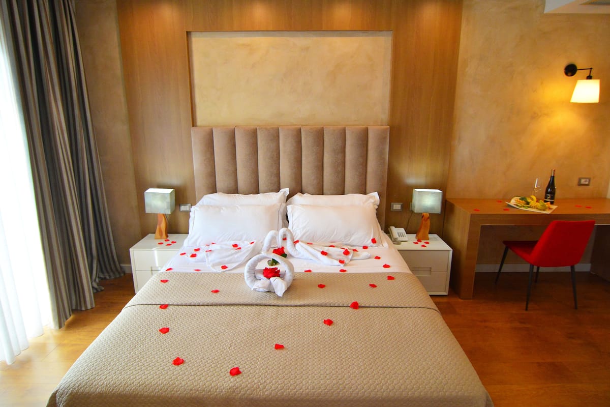 A hotel room with a large bed, a desk, and a chair.