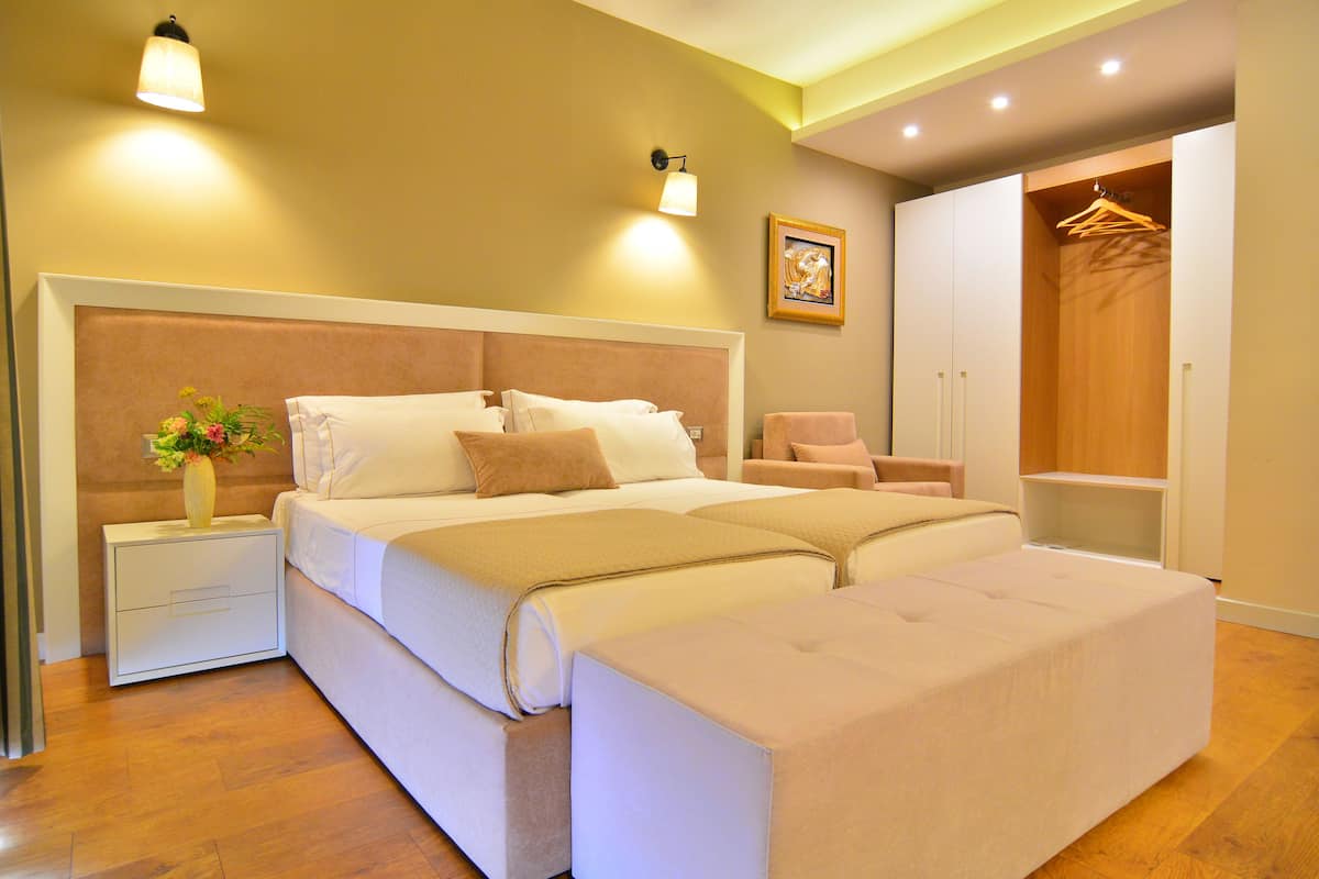 A modern bedroom with a large bed, bedside tables, a wardrobe, and a hanging closet.