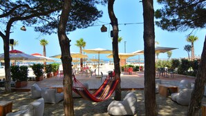 A beachside patio with hammocks, lounge chairs, and umbrellas.