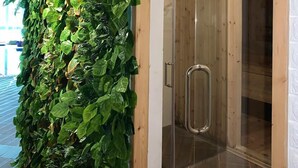 A wooden door with a sign reading "SAUNA" and a glass door leading inside.