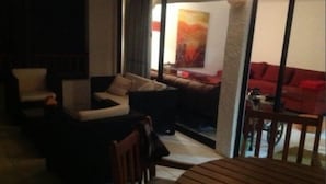 A cozy living area with a sofa set, a wooden table, and a red couch. - Depto Maria Salas Puerto Velero (Coquimbo)
