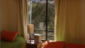 A room with two beds, a nightstand, and a window with curtains. - Depto Maria Salas Puerto Velero (Coquimbo)