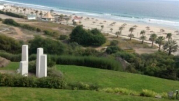 A coastal landscape with a beach, grassy areas, and a distant shoreline. - Depto Maria Salas Puerto Velero (Coquimbo)
