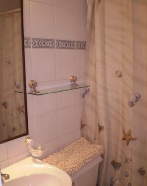 A bathroom with a sink, mirror, and two glass shelves. - Depto Maria Salas Puerto Velero (Coquimbo)
