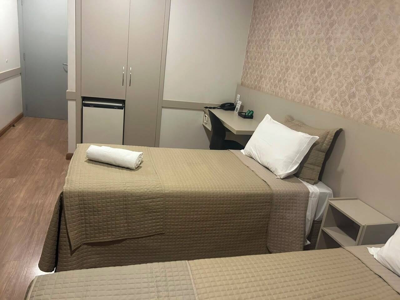 Habitación de hotel con dos camas, un escritorio pequeño, un armario y una pared con diseño.