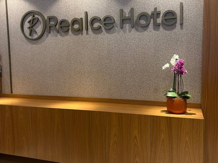 Een receptiebalie met een bord waarop 'Realce Hotel' staat en een potorkidee op de balie.