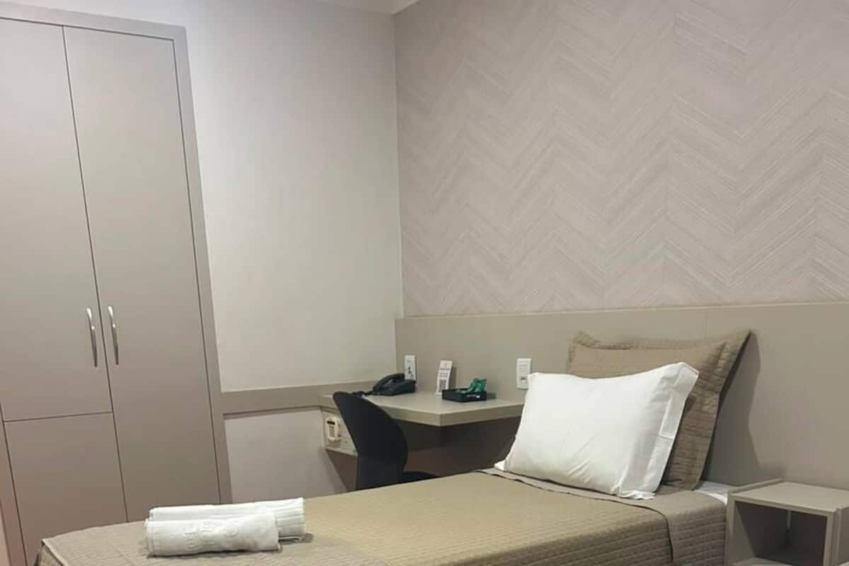 Hotellihuone, jossa on kaksi sänkyä, työpöytä, tuoli ja vaatekaappi.