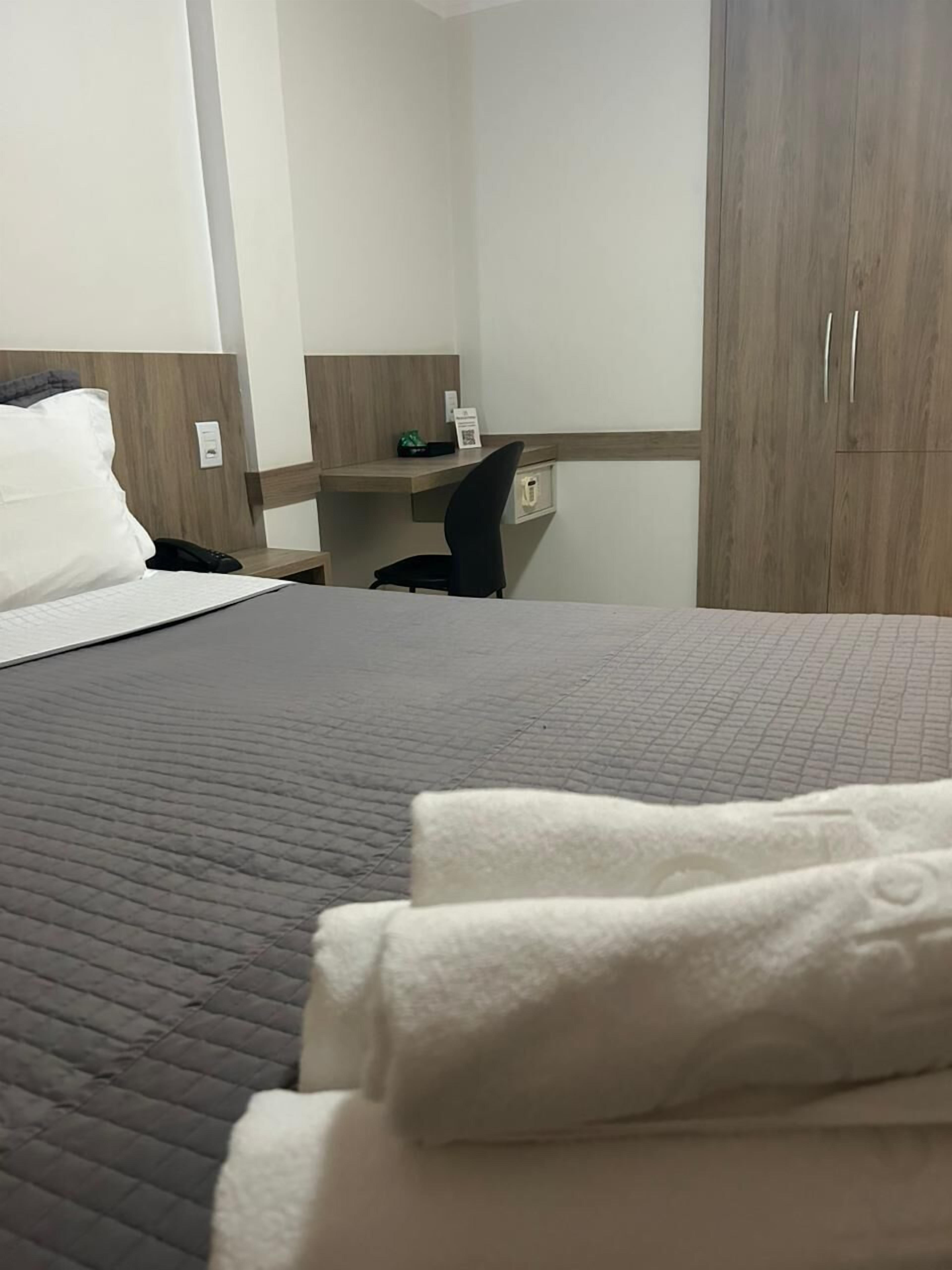 A hotel room with a bed, a desk, and a wardrobe.
