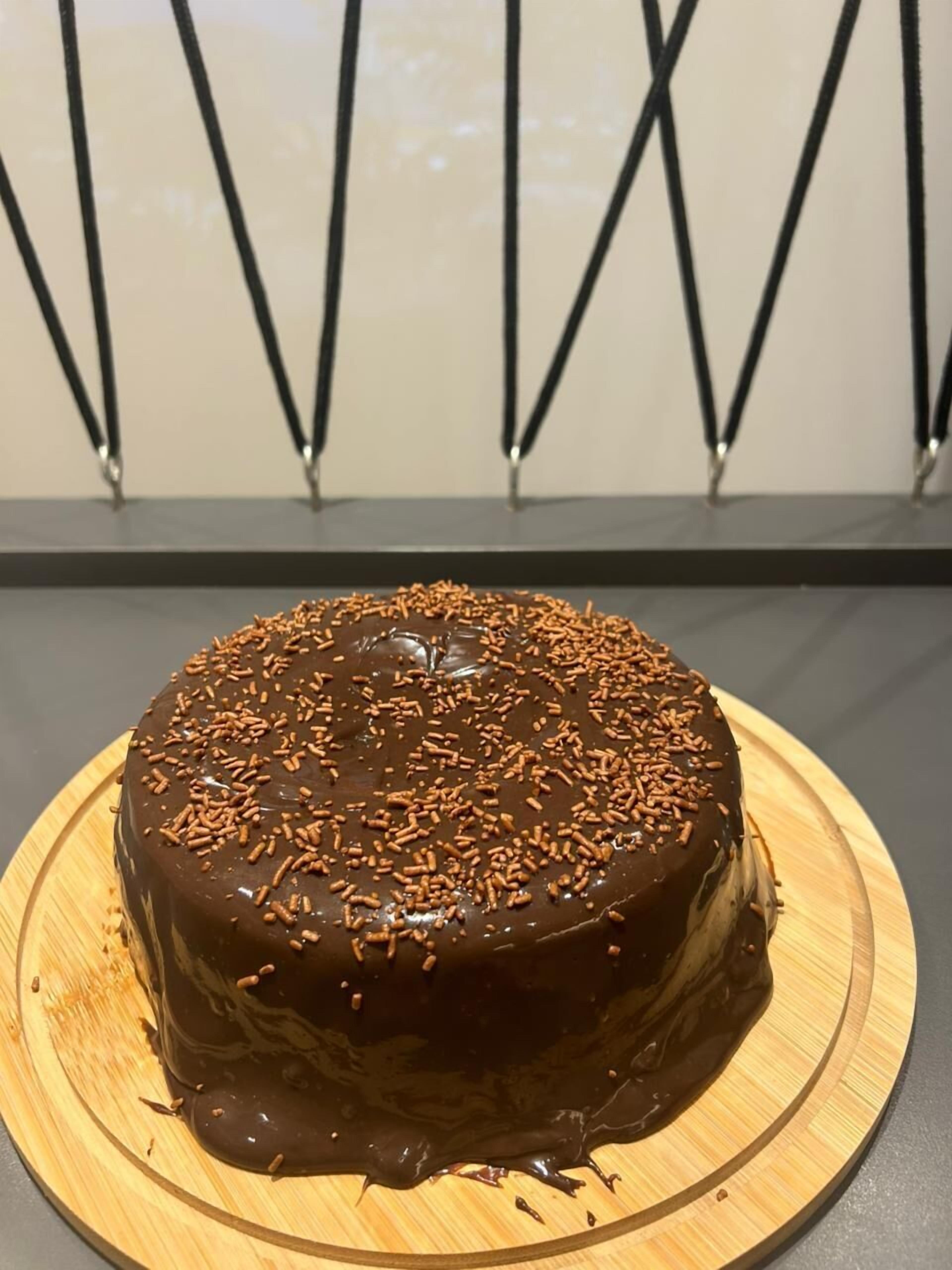 A chocolate cake with sprinkles on a wooden board.