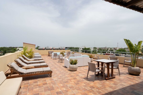 Una terraza en la azotea con sillones, una mesa y plantas en macetas.