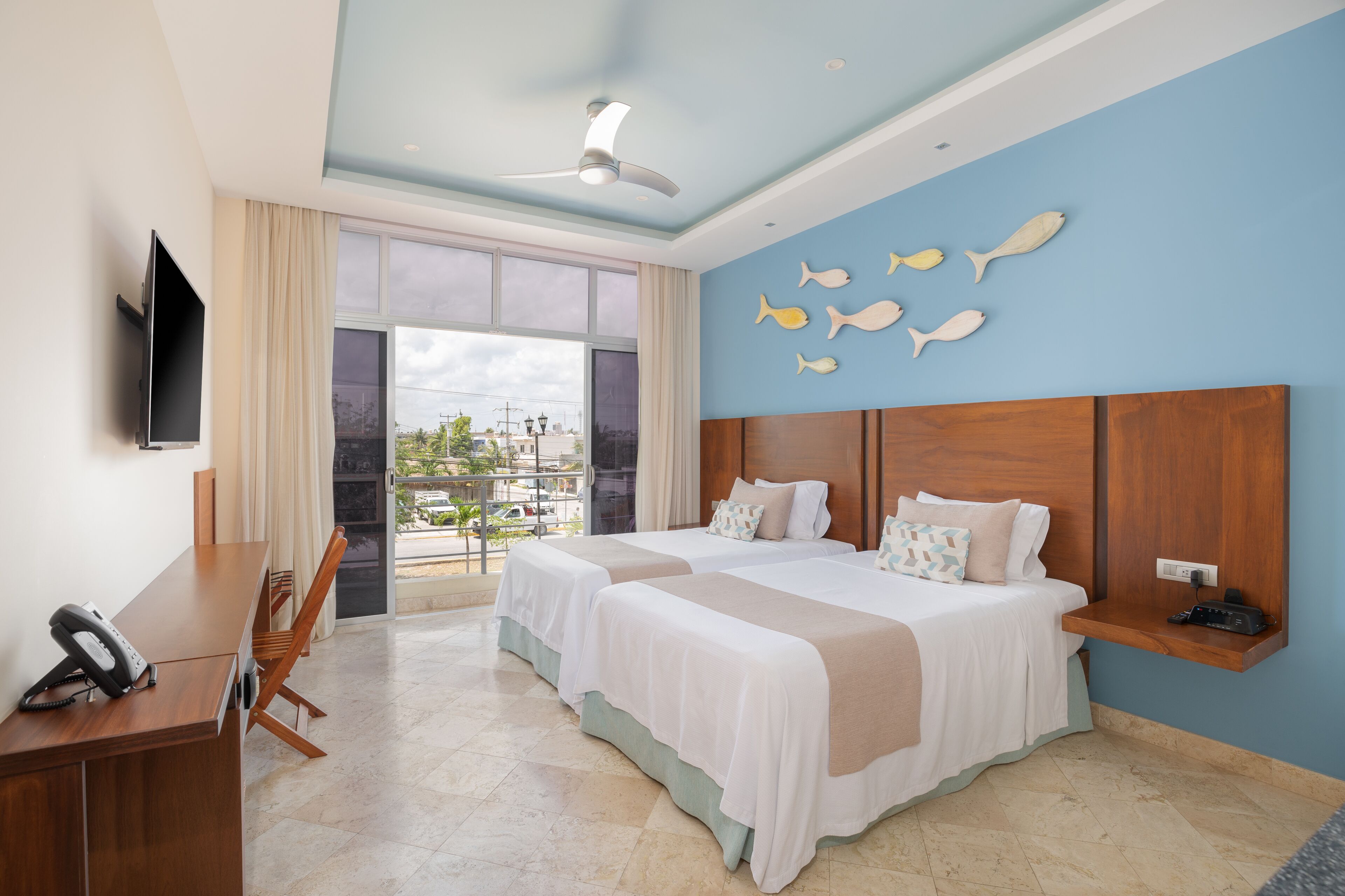 Una habitación de hotel con dos camas, un escritorio, un televisor y un balcón con vistas.