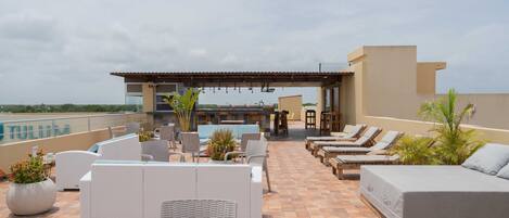 A rooftop terrace with outdoor seating, a pool, and a bar area.